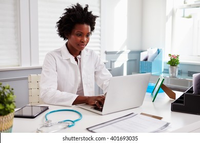 Black Female Doctor Wearing White Coat At Work In An Office