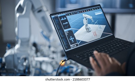 Black Female Engineer Using Laptop For Programming Robotic Arm At The Modern Assembling Factory. New Generation Of Advanced Technology In Automatic Manufacturing Industry Concept.