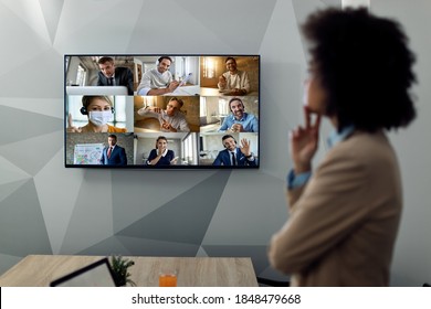 Black Female Entrepreneur Having Video Conference Call With Large Group Of Her Colleagues Over Projection Screen In The Office. Focus Is On The Screen.