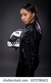 Black Female Motorcycle Rider Or Race Car Driver Wearing A Racing Helmet And Leather Jacket. Part Of The Gritty Woman Series, A Competitive Biker Or Racer Getting Ready For Competition.