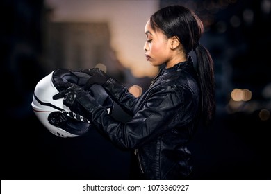 Black Female Motorcycle Rider Or Race Car Driver Wearing A Racing Helmet And Leather Jacket. Part Of The Gritty Woman Series, A Competitive Biker Or Racer Getting Ready For Competition.