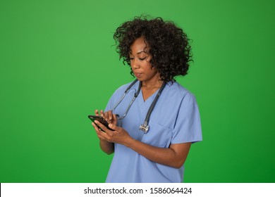 Black Female Nurse Checking Her Messages On Mobile Phone. Portrait Of Hospital Employee Using Smartphone On Greenscreen