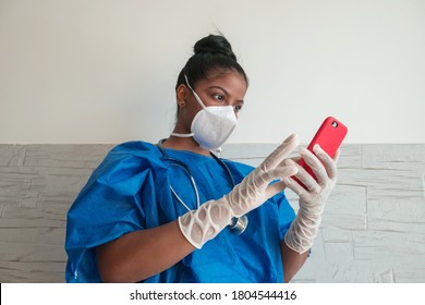 Black Female Nurse Checking Her Messages On Mobile Phone. Black Nurse