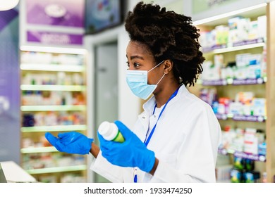 Black Female Pharmacist With Protective Mask On Her Face Working At Pharmacy. Medical Healthcare, Coronavirus, Covid-19 Concept.