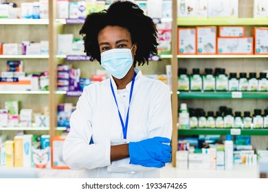 Black Female Pharmacist With Protective Mask On Her Face Working At Pharmacy. Medical Healthcare, Coronavirus, Covid-19 Concept.