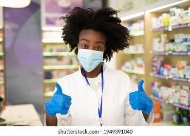 Black Female Pharmacist With Protective Mask On Her Face Working At Pharmacy. Medical Healthcare, Coronavirus, Covid-19 Concept.