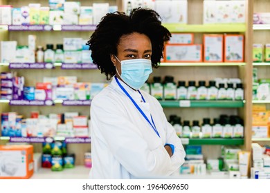 Black Female Pharmacist With Protective Mask On Her Face Working At Pharmacy. Medical Healthcare, Coronavirus, Covid-19 Concept.