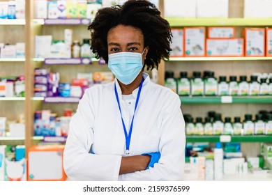 Black Female Pharmacist With Protective Mask On Her Face Working At Pharmacy. Medical Healthcare, Coronavirus, Covid-19 Concept.