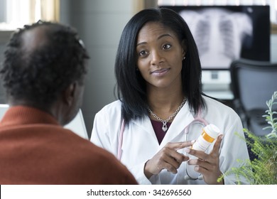 A Black Female Physician Prescribing Pills To An Older Black Male Patient