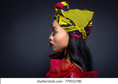 Black Female Showing African Pride By Wearing Nigerian Traditional Clothing And Tribal Makeup Or Face Painting.  The Model Is Shot In Studio In Modern Vogue Fashion Style.