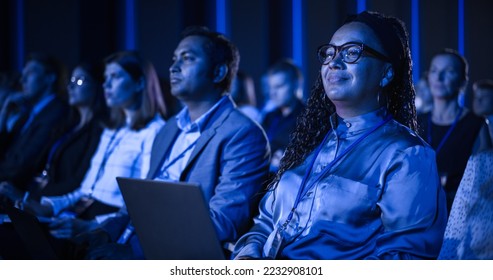 Black Female Sitting in Dark Crowded Auditorium at an International Business Conference. Multiethnic African Woman Using Laptop Computer. Delegate Watching Presentation About New Financial Solutions. - Shutterstock ID 2232908101