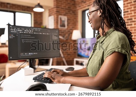 Black female software developer codes securely from home office, using computer to review programming scripts. African american IT freelancer working on tech solutions in modern apartment.