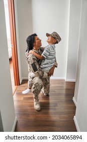 Black Female Soldier Holds Son On Arms At Home