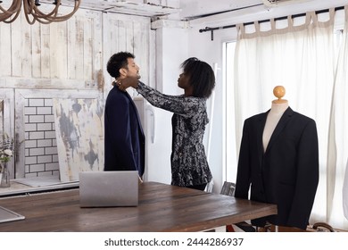 Black female tailor fitting businessman for suit in tailor shop - Powered by Shutterstock