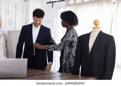 Black female tailor fitting businessman for suit in tailor shop - Powered by Shutterstock