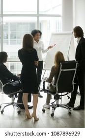 Black Female Team Leader Teaching Diverse Business People At Meeting, Multiracial Executive Group Listening To African Employee Explaining New Idea With Flipchart At Corporate Training, Vertical View