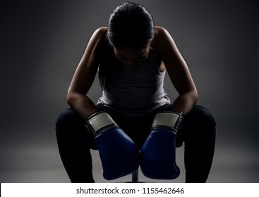 Black female wearing boxing gloves looking angry as a boxer, MMA fighter or self defense trainer sitting after working out.  She is portraying female strength and determination.  - Powered by Shutterstock