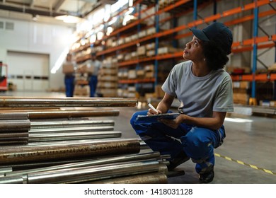 Black Female Worker Going Through Check List And Writing Notes While Working In A Warehouse. 