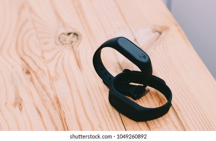 Black fitness tracker. Isolated. Healthy lifestyle. Fitness trackers lying on yellow wooden table. Healthcare, training, workout. Close-up photo. 