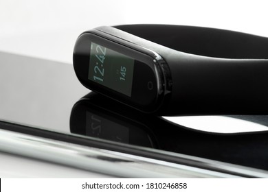 Black Fitness Watch Or Activity Tracker With Time And Steps On Display. Fitness Tracker Lies On The Smartphones. Closeup, Selective Focus