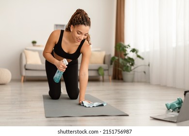 Black Fitness Woman Cleaning Gymnastics Mat With Rag And Detergent Before Workout At Home. Fit Lady Sanitizing Sport Equipment. Gym And Hygiene Concept