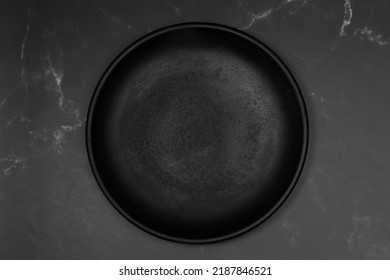 Black Flat Plate On A Black Marble Kitchen Counter In A Top View