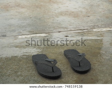 black flip flops on cement with the rains