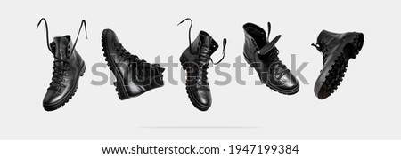 Black flying leather men's or women's boots isolated on light gray background. Fashionable stylish hiker boots. Creative minimalistic shoes background. Rough unisex boots. Layout with footwear Mock up