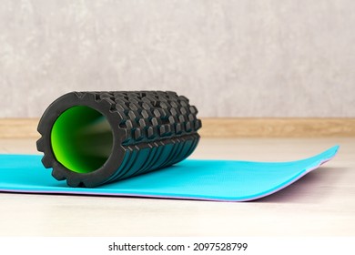 Black Foam Roller For Self-massage On Blue Yoga Mat. Equipment For Myofascial Release. Fitness Equipment. Side View.