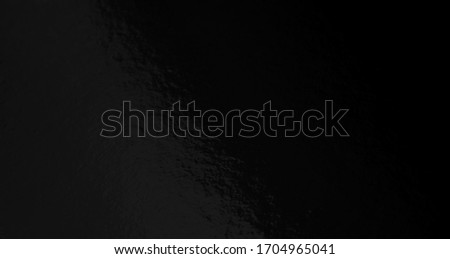 Black foil texture background with uneven surface