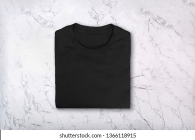 Black Folded Tshirt On Marble Background. Blank Black Cotton Tee-shirt On Marble Texture