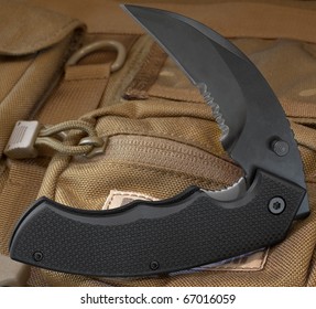 Black Folding Knife That Is On A Case Of Ballistic Nylon