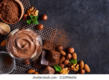 Black food background with cocoa, nuts and chocolate paste. top view