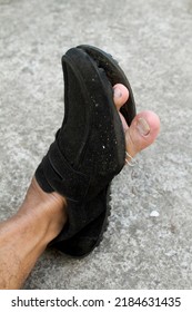 Black Formal Shoes Made Of Broken Leather With A Hole In The Front So That The Big Toe Of His Left Is Visible