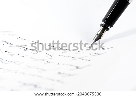 Black fountain pen is writing a letter or a manuscript on a white paper, copy space, close-up shot with selected focus and narrow depth of field