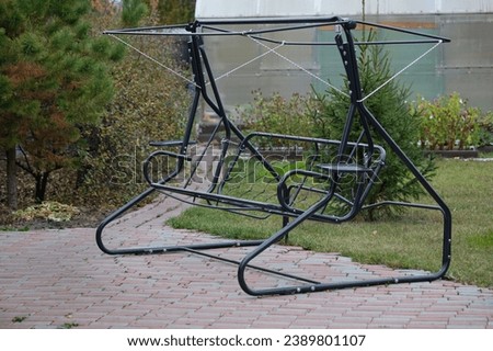 black frame of metal swing in the garden