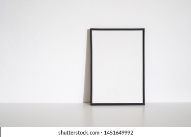 Black Frame Poster On Table In White Room