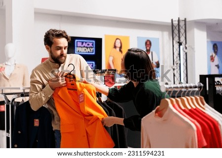 Black Friday fight. People shoppers fighting over clothes during big sales in mall, angry man and woman customers pulling clothing item and arguing while shopping in store during seasonal discounts