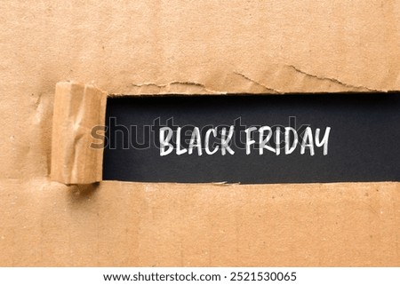 Black friday message written on ripped torn cardboard paper with black background. Conceptual black friday symbol. Copy space.