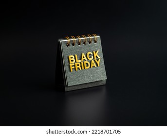 Black Friday sale concept. BLACK FRIDAY, golden text bas-relief on small black spiral desk calendar cover standing on dark background, minimalist. Invitation card, poster and banner.