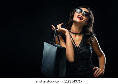 Black friday sale concept. Shopping woman holding grey bag isolated on dark background in holiday - Shutterstock ID 1192343719