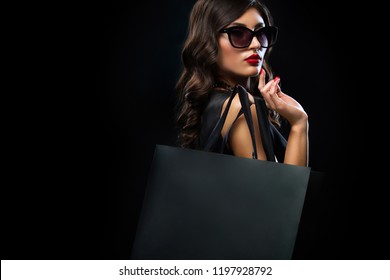 Black friday sale concept. Shopping woman holding grey bag isolated on dark background in holiday