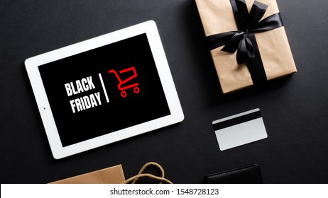 Black Friday sale concept. Tablet with sign "Black Friday" on screen, shopping bag and credit card over black background. Flat lay, top view, overhead. - Powered by Shutterstock