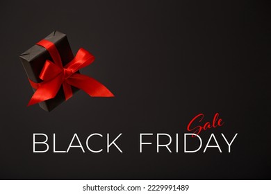 Black Friday sale. Black gift box with red bow floating in air on black background. Discount, online shopping concept