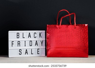 Black Friday sale. Red shopping bag and lightbox on dark background. - Powered by Shutterstock