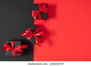 Black friday sales concept. Top view on composition of black gift boxes with red ribbon on black and red background. Shopping sale  concept. Flat lay, copy space - Powered by Shutterstock