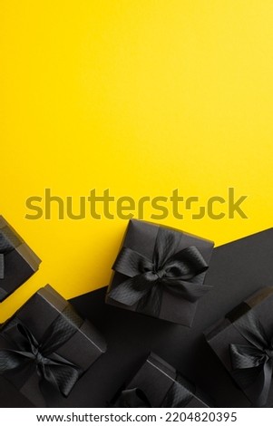 Black friday sales concept. Top view vertical photo of black gift boxes with ribbon bows on bicolor yellow and black background with copyspace