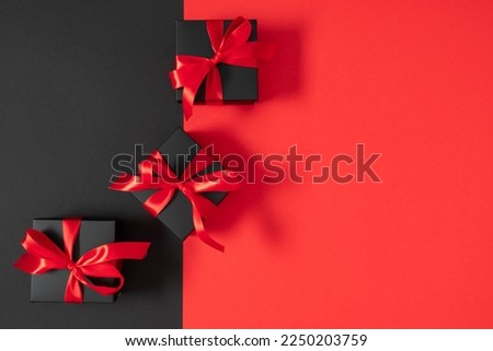 Black friday sales concept. Top view on composition of black gift boxes with red ribbon on black and red background. Shopping sale  concept. Flat lay, copy space