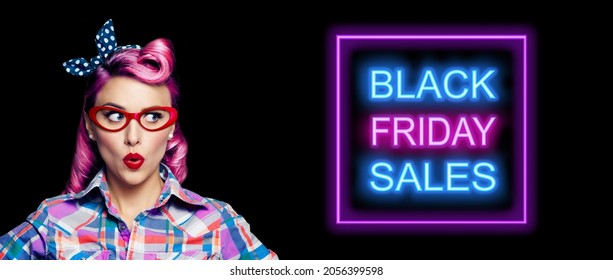 Black Friday Sales, discounts, rebates, trade deals concept - excited surprised pin up woman in red glasses looking sideways. Purple hair girl in pinup rockabilly style. Neon light sign. Wide image. - Shutterstock ID 2056399598