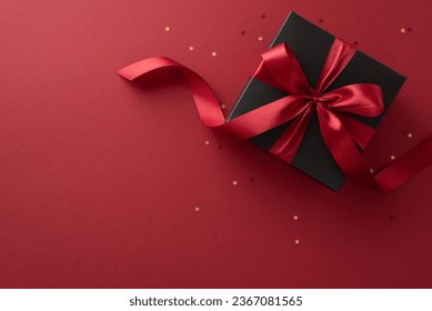 Black Friday surprise: Top view of a deluxe black gift box featuring a stylish red ribbon and gold confetti on a marsala background, offering an ideal spot for your text or ad - Powered by Shutterstock